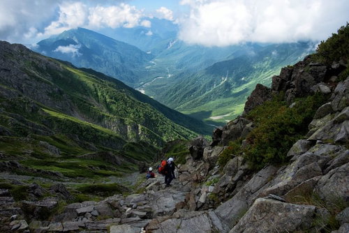 ガレ場に挑む登山者と青空の山岳風景