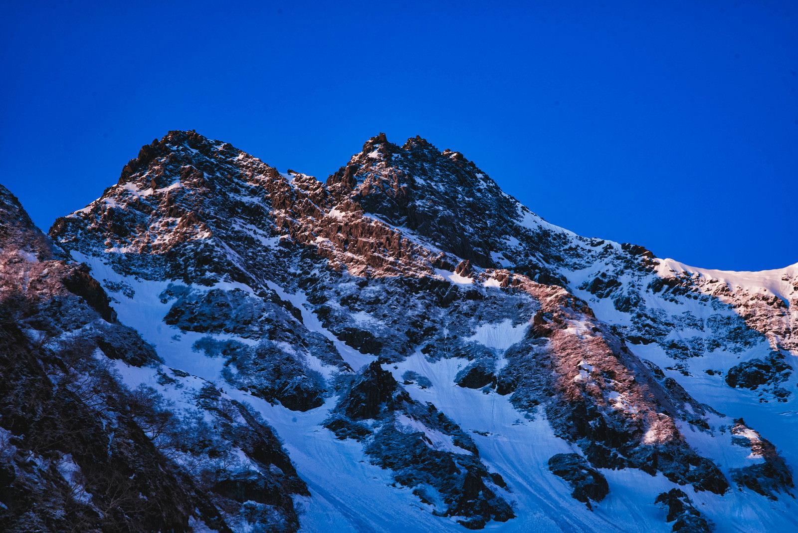 Snow-covered rocky ridge of Zaitenguratto against a blue sky