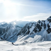 涸沢カールを照らす太陽と雪山の冬景色と登山者の写真