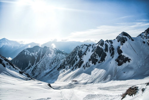 涸沢カールを照らす太陽と雪山の冬景色と登山者
