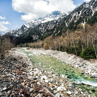 どこまでも続く梓川と残雪の明神岳、北アルプスの雄大な風景の写真