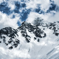 冬の北アルプス・前穂高岳にかかる雲と積雪の山肌の写真