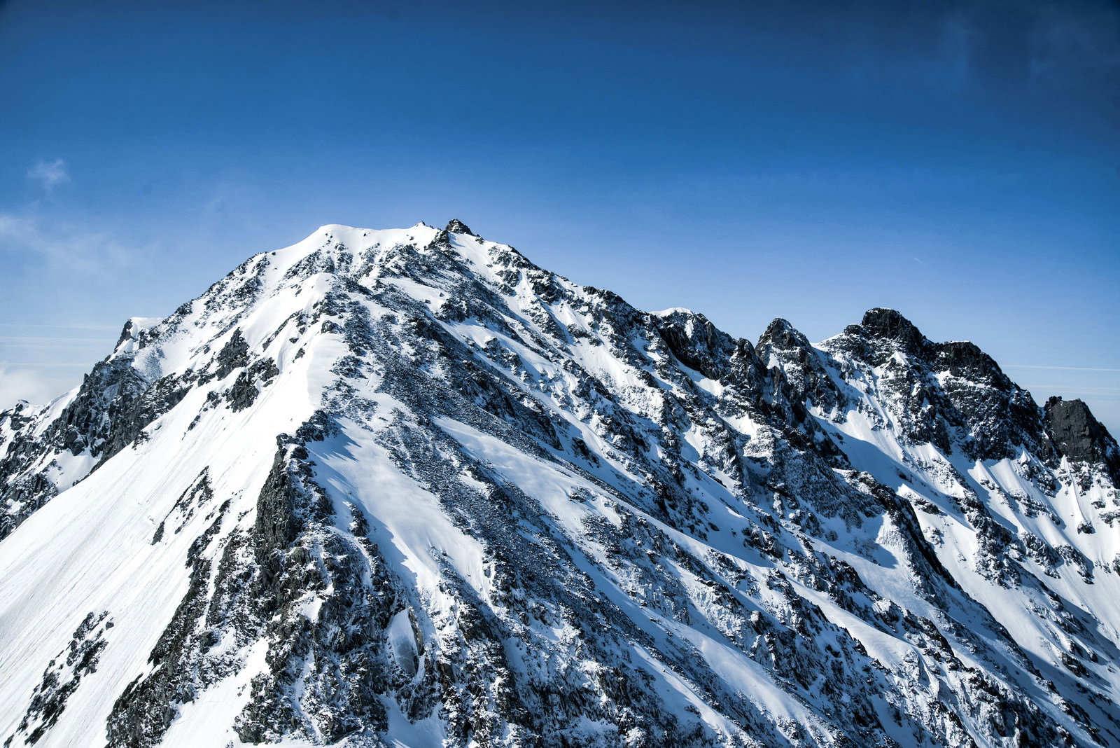 雪に覆われた奥穂高岳とジャンダルムの岩稜が青空の下に連なる山岳風景