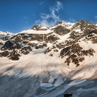 太陽が差す奥穂高岳の断崖、積雪に照らされた冬の飛騨山脈の写真
