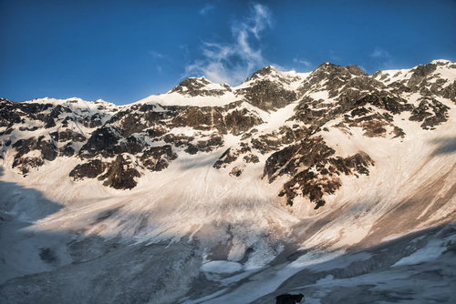 太陽が差す奥穂高岳の断崖、積雪に照らされた冬の飛騨山脈