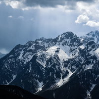 雲間からの光に照らされる雪化粧の前穂高岳（北アルプス）の写真