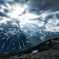 雲間から降り立つ天使のはしごと雪化粧した飛騨山脈の写真