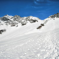 残雪期の奥穂高岳とザイテングラード、登山者の足跡が続く岩尾根の写真