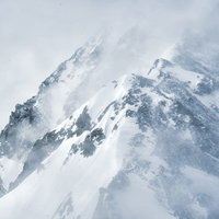 吹雪く視界不良の雪山の登山道の写真