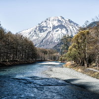 梓川の先に見える春の焼岳と残雪の山岳風景の写真