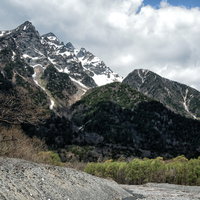 新緑に包まれた明神岳と残雪が映える登山風景の写真