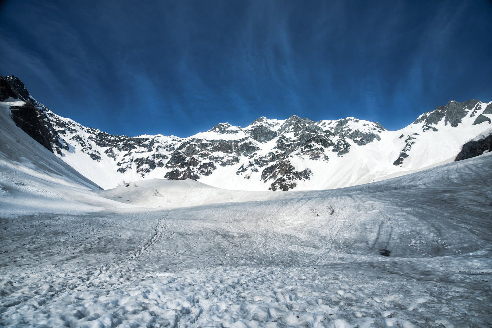 雪渓に覆われた涸沢の谷間、周囲を雪山に囲まれた白い雪面