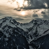冬山の大キレットに沈むオレンジ色の夕日と雪景色の写真
