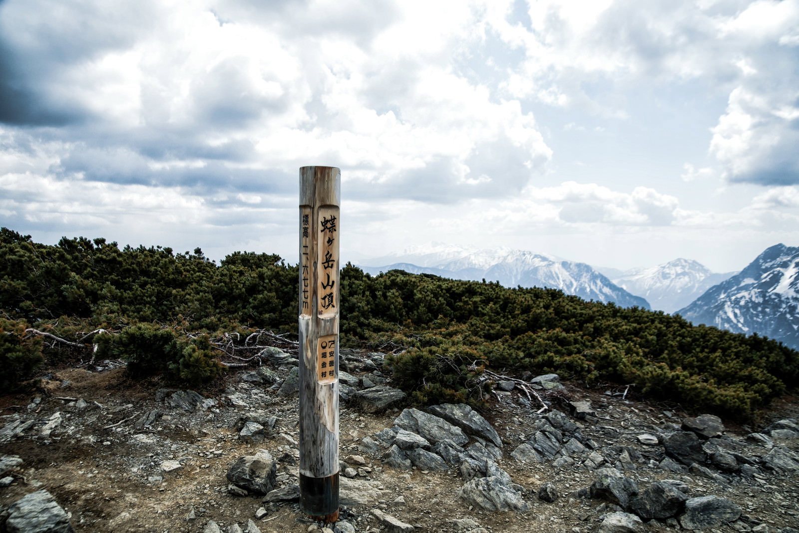 蝶ヶ岳山頂に立つ木製の標識と背景の山々