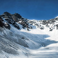 涸沢に伸びる影と残雪期の吊尾根（北アルプス）の写真