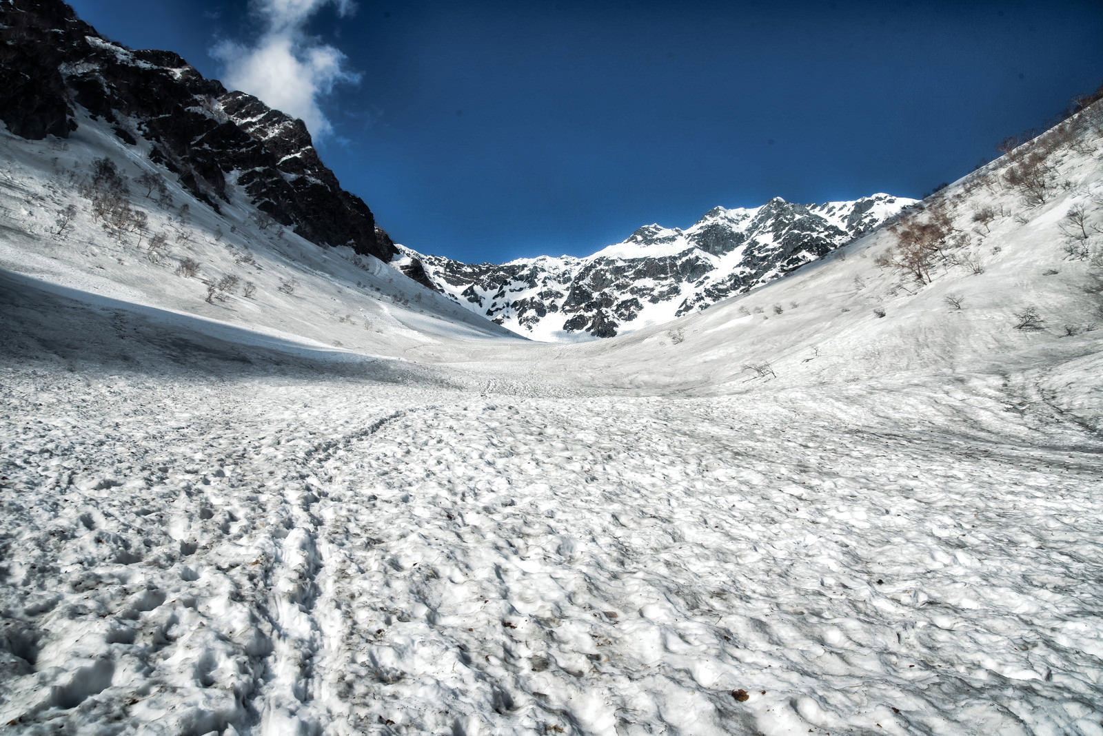 涸沢へ続く残雪のトレースと青空に映える雪山