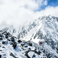涸沢岳から見下ろす奥穂高岳山荘の冬景色と残雪の山々の写真
