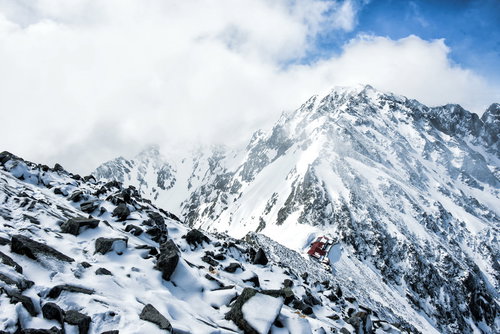 涸沢岳から見下ろす奥穂高岳山荘の冬景色と残雪の山々