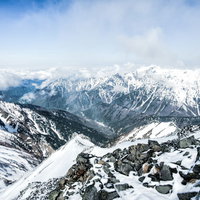 雪に覆われた北アルプス・涸沢岳頂上から眺める笠ヶ岳の写真