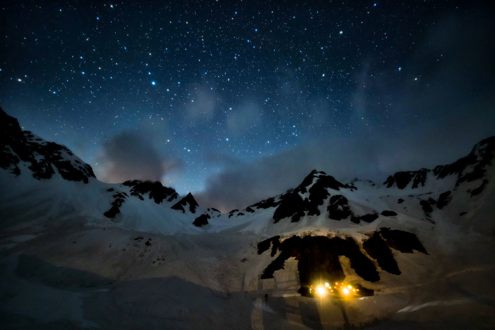 雪山に建つ涸沢ヒュッテの明かりと満天の星空が美しい冬の夜景