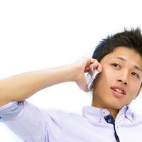 電話で確認を取る薄紫のシャツを着た青年の写真