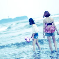 波打ち際の浅瀬で手をハートの形にして遊ぶ女子の写真