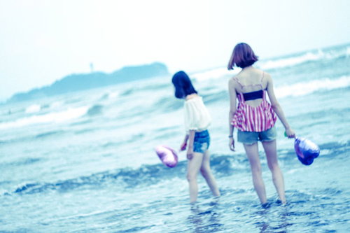 波打ち際の浅瀬で手をハートの形にして遊ぶ女子