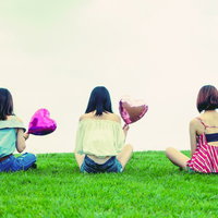 ハートの風船を持った女性3人の後姿、夏の芝生で友情を表現の写真