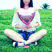 芝生に座るガーリー女子とピンクのハート型風船の写真