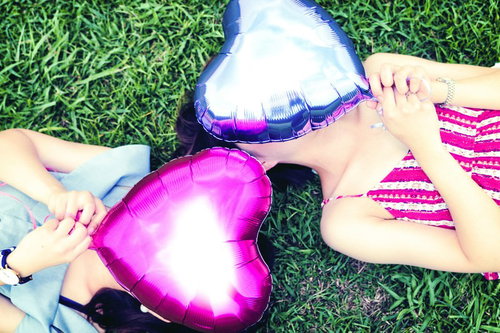 ピンクのハートで顔を隠すガーリーな女性二人組