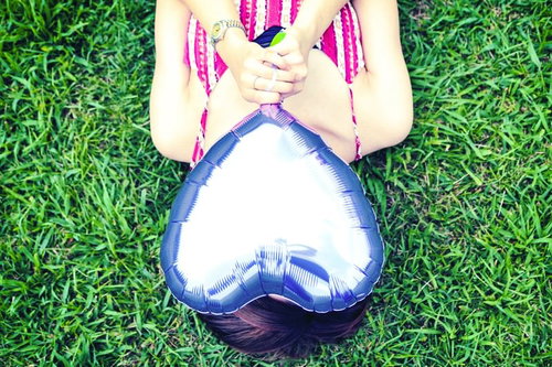 草原で本を持って手でハートを作る告白せずに想いを伝える女性