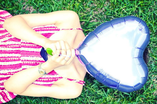 青いハート型の風船で顔を隠すピンクのボーダー服の女子