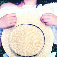 緑の芝生で麦わら帽子を抱える女性のポートレートの写真