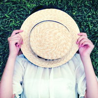 麦わら帽子で顔を隠す女の子の夏のポートレートの写真