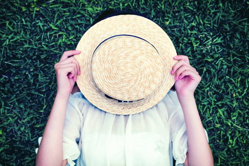 麦わら帽子で顔を隠す女の子の夏のポートレート