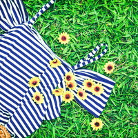 青白ストライプの夏服に付けた黄色い花のブローチの写真