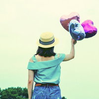 風船のハートで飛んでいきたい麦わら帽子の女性の写真