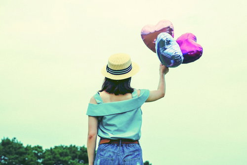 風船のハートで飛んでいきたい麦わら帽子の女性