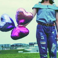 ハートの風船を手に持ったダメージジーンズ女子の写真