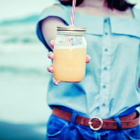 波打ち際の浅瀬で手をハートの形にして遊ぶ女子の写真