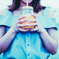 ドリンクジャーをごくごく飲む青いシャツの女性の写真