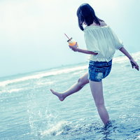 浅瀬で海面を蹴り上げる女性が楽しむ夏の海辺の写真