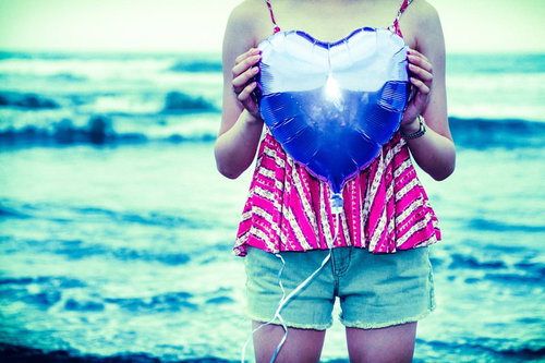 海岸の砂浜でカラフルなハートを抱えた女子