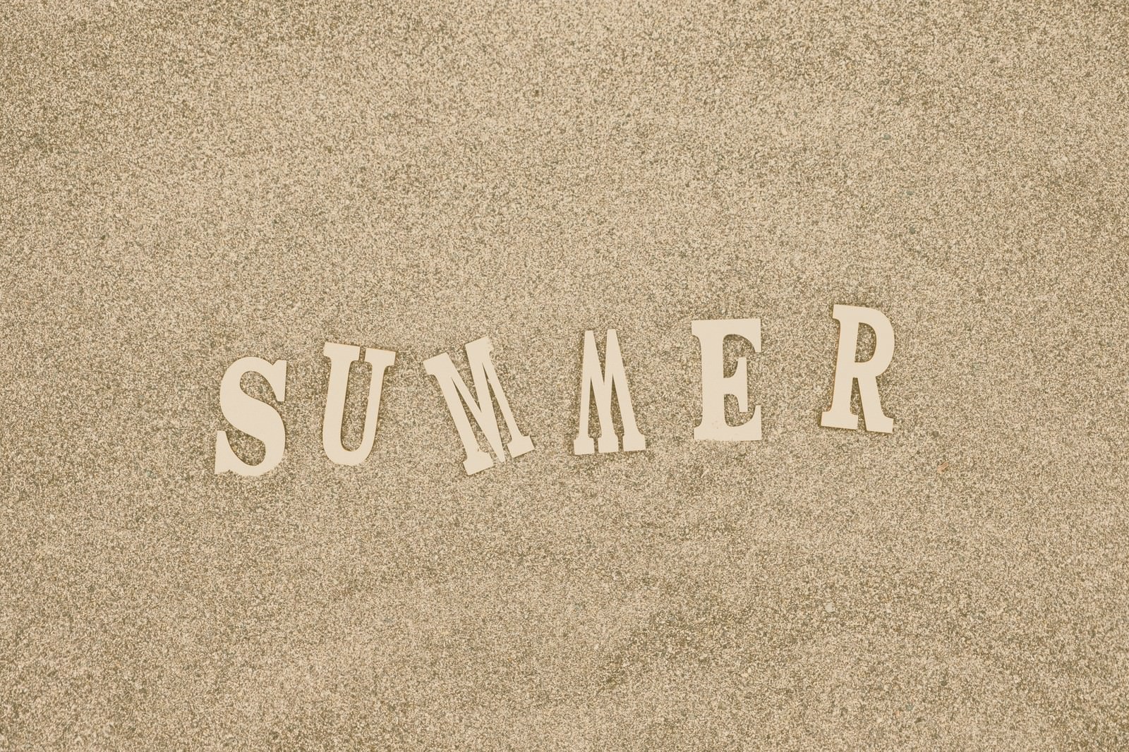 砂浜に白い文字で書かれたSUMMERのテキスト