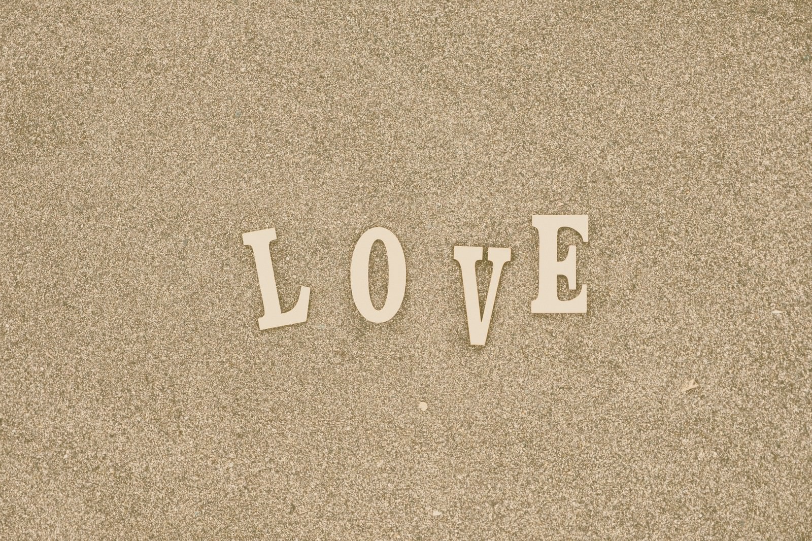 ベージュ色の砂にホワイトで書かれたLOVEの立体文字
