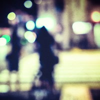 夜間の横断歩道で信号待ちする人のシルエット（ボケ）の写真