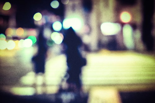 夜間の横断歩道で信号待ちする人のシルエット（ボケ）