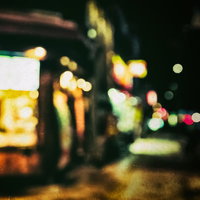 深夜営業のお店の看板をボケで捉えた夜間の街並みの写真