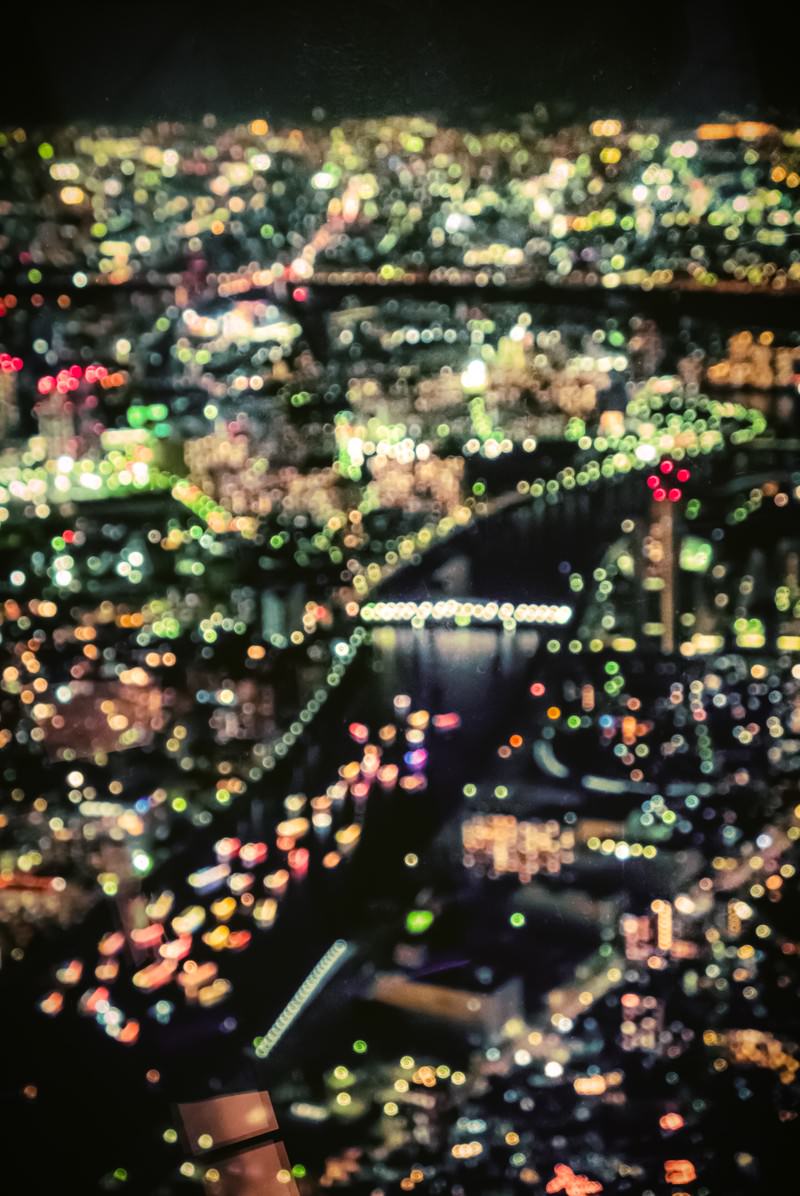 都市の夜景を丸ボケで撮影した写真。街の明かりが光の粒となって広がる幻想的な夜景
