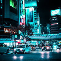 渋谷駅前のスクランブル交差点を走る車のヘッドライトと夜景の写真